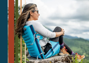 Woman reclining comfortably in her aircliner chair in front of a green valley