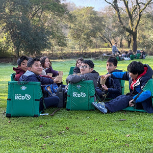 Custom crazy creek chairs made for a group of smiling kids sitting in a field