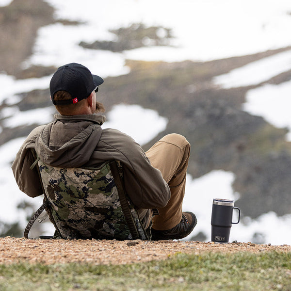 Man sitting in a camo chair on a snowy mountainside