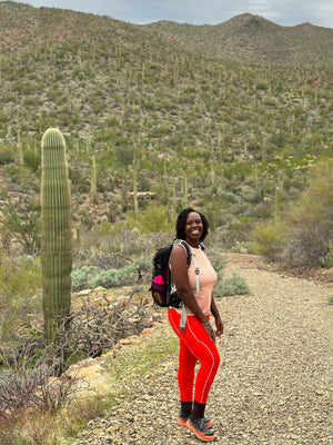 Woman smiling posing in front of a cactus in a desert
