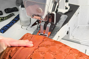 Closeup of a sewing machine repairing an orange crazy creek chair