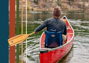 Closeup of the back of the Canoe IV paddle chair and a man navigating down a river