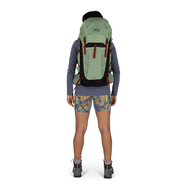 Backpacking woman carrying the Osprey and Crazy Creek Collab backpack full body -looking at back - on white