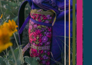 Floral-patterned Hex 2.0 floral print crazy creek chair attached to a purple backpack in a natural setting