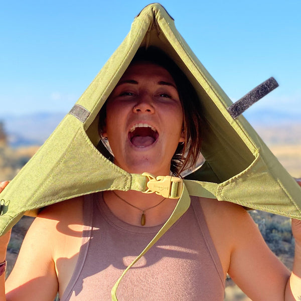 Woman wearing a Crazy Creek chair like a hat while houting