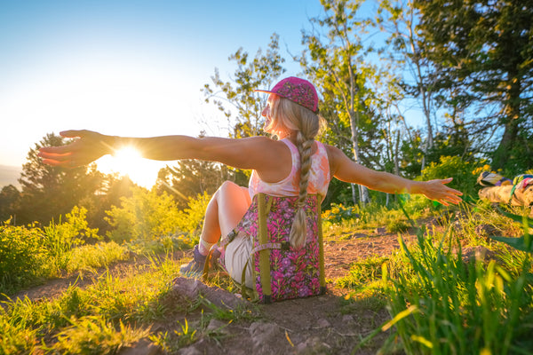 Woman sitting in nature with arms outstretched, enjoying the sun.