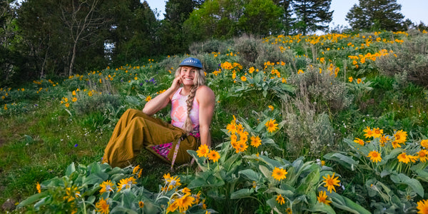 Rachel Pohl sitting in a field of yellow flowers in a natural setting