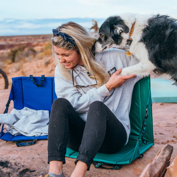 Cute girl sitting in a chair with her dog jumping up next to her