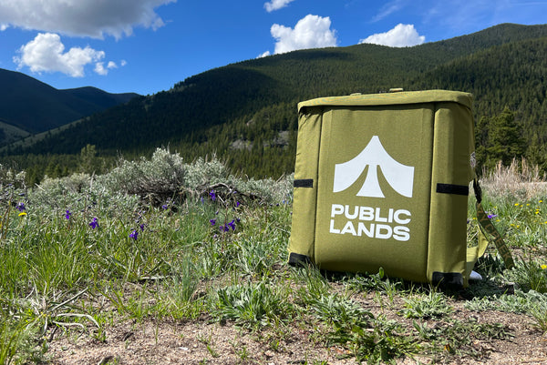 A custom Crazy Creek chair with Public Lands printed on it sitting in front of a beautiful hillside