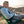 Man sitting in a green chair while looking at his phone on a mountain