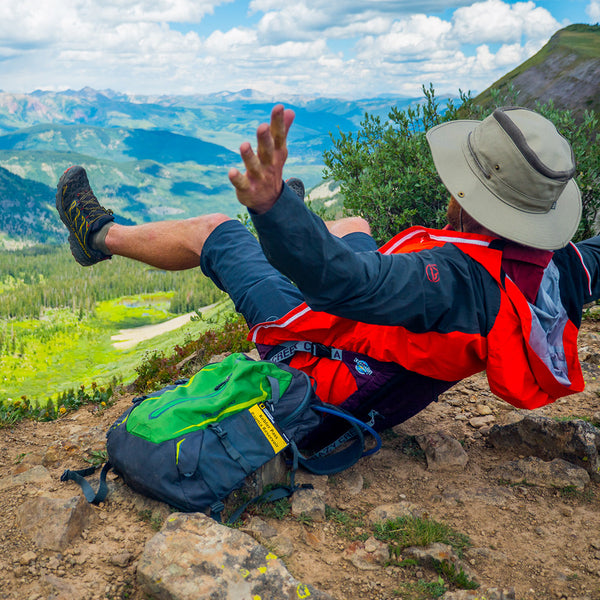 Man reclining in a chair on the edge of beautiful green mountains while raising his arms out
